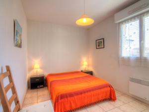 a bedroom with a orange bed and two lamps at Apartment Maria Callas by Interhome in Labenne