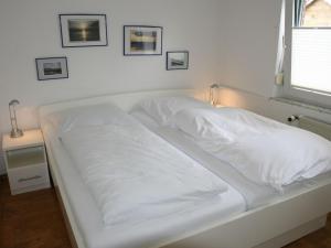 ein weißes Bett mit weißer Bettwäsche und einem Fenster in der Unterkunft Holiday Home Norderney by Interhome in Norddeich