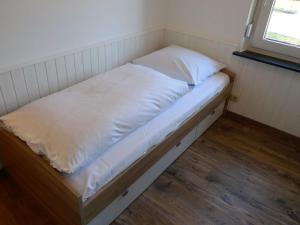 ein kleines Bett mit weißer Bettwäsche und einem Fenster in der Unterkunft Holiday Home Norderney by Interhome in Norddeich