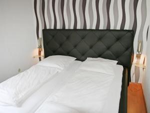 Bett mit schwarzem Kopfteil und weißer Bettwäsche in der Unterkunft Holiday Home Norderney by Interhome in Norddeich