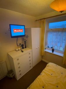 a bedroom with a bed and a television on a dresser at Highbury Hotel in Blackpool