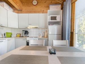 uma cozinha com armários brancos e uma mesa com cadeiras em Holiday Home Vuosselinkulma 2 by Interhome em Ruka