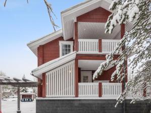 een rood huis met een witte veranda in de sneeuw bij Holiday Home Kätkänlinna a2 by Interhome in Levi