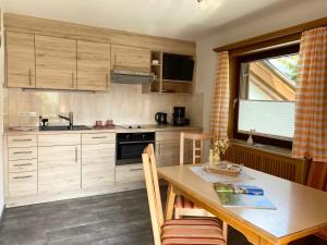 cocina con armarios de madera, mesa y ventana en Apartment Hubert Praxmarer, en Fulpmes