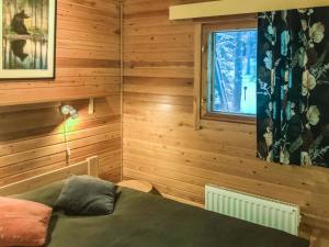 ルカにあるHoliday Home Pikku-metso by Interhomeの木製の壁のベッドルーム1室、窓付きのベッド1台が備わります。