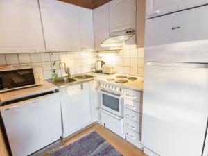 ユッラスヤルヴィにあるHoliday Home Tunturinvieri k3 by Interhomeの白いキャビネット、シンク、冷蔵庫付きのキッチンが備わります。