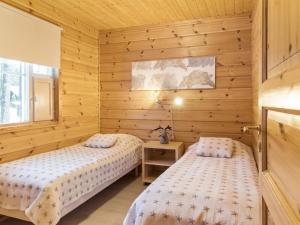 zwei Betten in einem Zimmer mit Holzwänden in der Unterkunft Holiday Home Luppo by Interhome in Ylläsjärvi