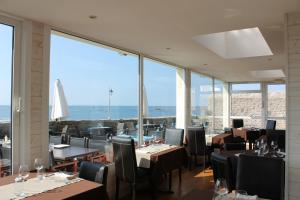 un restaurante con mesas, sillas y ventanas grandes en Le Poisson d'Avril, en Le Guilvinec