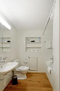 a white bathroom with a toilet and a sink at Apartment Gade A by Interhome in Lenk