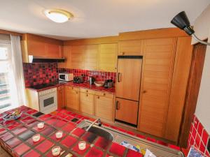 ツェルマットにあるApartment Lani by Interhomeの赤いタイルフロアのキッチン(木製キャビネット付)