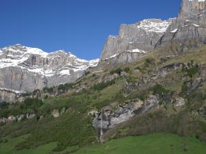 a mountain range with a green field and snow covered mountains at Apartment Ringstrasse - Utoring-46 by Interhome in Leukerbad