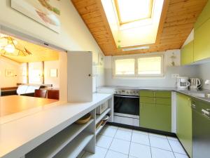 a kitchen with green cabinets and a wooden ceiling at Apartment Ringstrasse - Utoring-46 by Interhome in Leukerbad