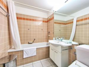 a bathroom with a sink and a tub and a toilet at Apartment Ringstrasse - Utoring-46 by Interhome in Leukerbad