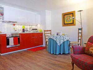 ベーヴァにあるStudio Chesa Rossa by Interhomeの赤いキャビネットとテーブル付きのキッチンが備わります。
