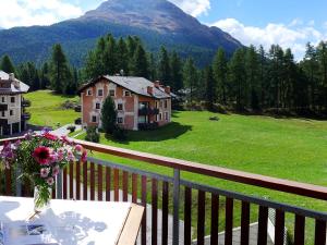 a table with a vase of flowers on a balcony at Apartment Chesa Vadret 12 by Interhome in Pontresina