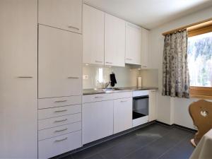 a white kitchen with white cabinets and a window at Apartment Chesa Islas by Interhome in Pontresina