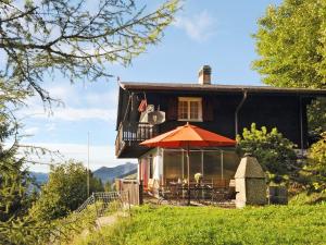 a house with a table and an umbrella in front of it at Chalet Bühlweidli by Ferienlenk in Lenk