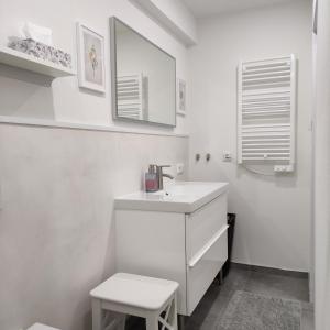 ein weißes Badezimmer mit einem Waschbecken und einem Stuhl in der Unterkunft Appartement Mond in Senftenberg