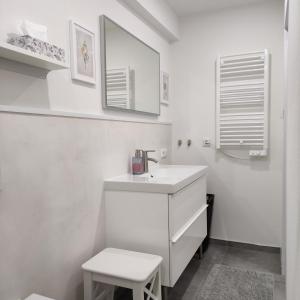 a white bathroom with a sink and a stool at Appartement Mond in Senftenberg