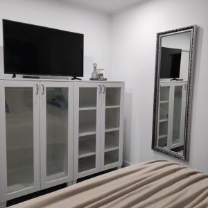 a white entertainment center with a television and a mirror at Appartement Mond in Senftenberg