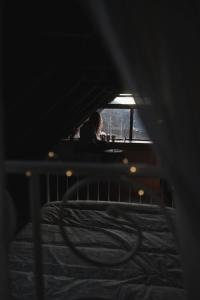 uma mulher sentada numa cama num quarto escuro em Albergue de Liri em Lirí