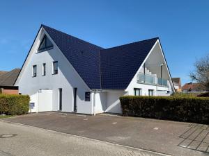 uma casa branca com um telhado preto em Apartment Witthuus-Norderney by Interhome em Norddeich