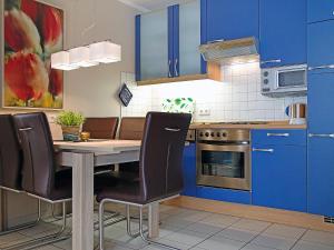 uma cozinha com armários azuis e uma mesa e cadeiras em Apartment Witthuus-Norderney by Interhome em Norddeich