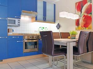 ノルトダイヒにあるApartment Witthuus-Juist by Interhomeのキッチン(青いキャビネット、テーブル、椅子付)
