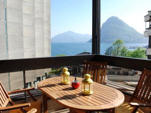 un tavolo in legno su un balcone con vista sull'oceano di Apartment Residenza Cassarate Lago-1 a Lugano