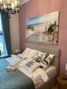 a bed in a bedroom with a painting on the wall at Apartament rodzinny in Gdańsk