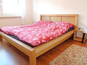 ein Bett mit einer roten Bettdecke darauf in einem Zimmer in der Unterkunft Apartment Im Spiet by Interhome in Norden