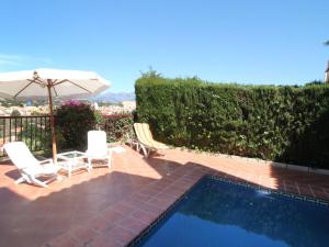 a swimming pool with two chairs and an umbrella at Holiday Home Mar y Montaña by Interhome in Benidorm