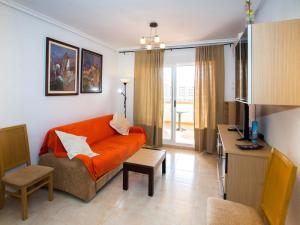 sala de estar con sofá naranja y mesa en Apartment Jardines del Mar I-1 by Interhome, en El Borseral