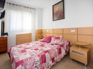 1 dormitorio con 1 cama con edredón rosa y blanco en Apartment Jardines del Mar I-1 by Interhome, en El Borseral