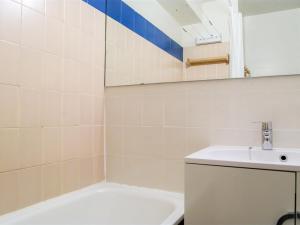 La salle de bains est pourvue d'un lavabo, d'une baignoire et d'un miroir. dans l'établissement Studio Le Triolet-6 by Interhome, à Chamonix-Mont-Blanc