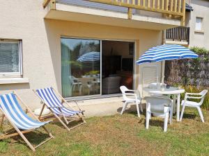 dos sillas y una mesa y una sombrilla en un patio en Apartment Les Galiotes-1 by Interhome, en Carnac-Plage
