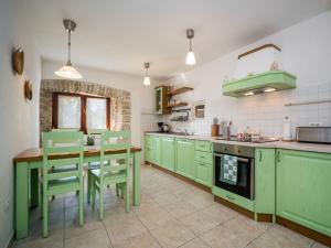 a kitchen with green cabinets and a table and chairs at Holiday Home Ivanka by Interhome in Čabrunići