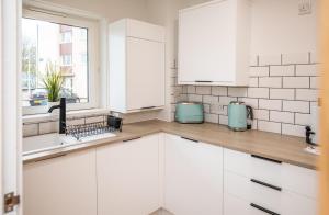 a kitchen with white cabinets and a window at James' Place at The Taff in Merthyr Tydfil