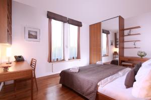 a bedroom with a bed and a desk and two windows at Rezidence Vyšehrad in Prague