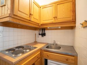 a kitchen with a sink and a stove and cabinets at Apartment Les Lauzes-3 by Interhome in Les Menuires