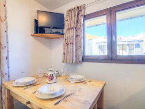 una mesa de madera con platos y gafas y una ventana en Studio Plein Soleil - Val Claret-9 by Interhome, en Tignes