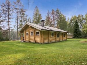uma cabana de madeira num quintal com um grande campo de relva em Holiday Home Uitonniemi- rummukkala by Interhome em Polvijärvi