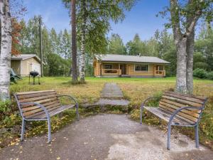 dois bancos sentados em frente a uma cabana de madeira em Holiday Home Uitonniemi- rummukkala by Interhome em Polvijärvi
