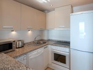 トロクス・コスタにあるApartment Magnificent front seaview- Torrox by Interhomeの白いキャビネット、シンク、冷蔵庫付きのキッチンが備わります。