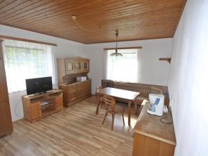 ein Wohnzimmer mit einem Tisch und einem TV sowie eine Küche in der Unterkunft Holiday Home Berg by Interhome in Obermieger