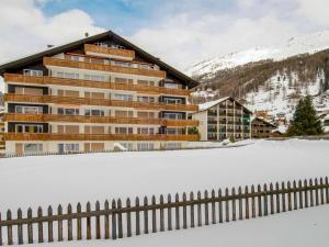 a building with a fence in the snow at Apartment Granit-5 by Interhome in Zermatt
