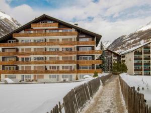 a building in the snow with a fence at Apartment Granit-5 by Interhome in Zermatt