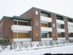 een rood bakstenen gebouw met witte balkons in de sneeuw bij Apartment Gezeiten by Interhome in Norddeich