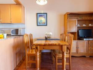 a kitchen with a wooden table with chairs and a television at Holiday Home Salvagina 53 by Interhome in Riumar +15 photos