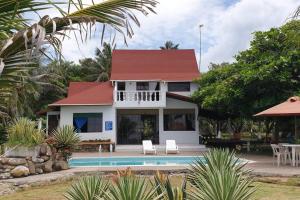 ein weißes Haus mit rotem Dach und einem Swimmingpool in der Unterkunft Cabaña PEDREGAL in Puerto Escondido